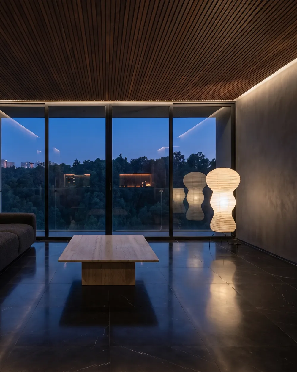 Estancia contemporánea con vista a un bosque al anochecer